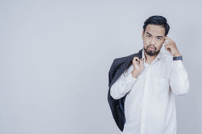 Portrait of young man standing against white background