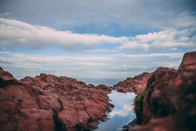 Rock formations by sea against sky