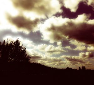 Silhouette of trees against cloudy sky