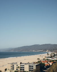 Scenic view of sea by buildings against clear sky