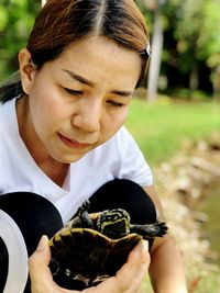 Close-up of woman holding turtle at park