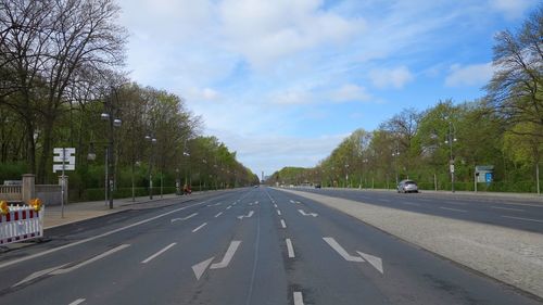 Road by trees against sky