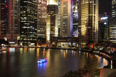 Illuminated buildings by river at night