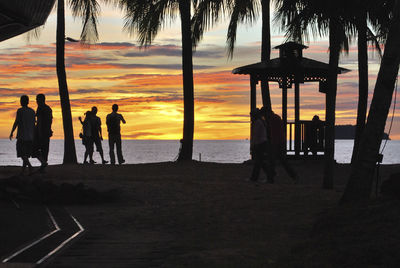 Silhouette people standing on beach during sunset