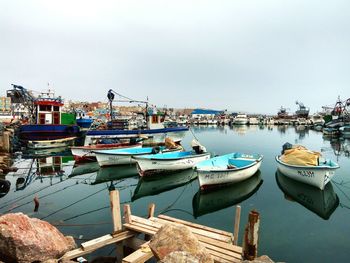 Boats moored at harbor against clear sky