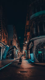 Illuminated street amidst buildings at night