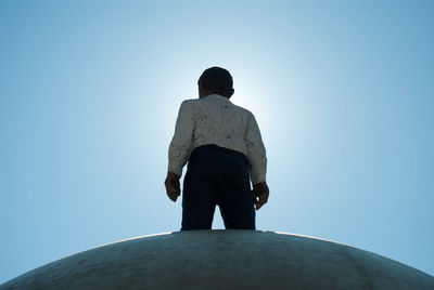 Low angle view of statue in front of building against blue sky