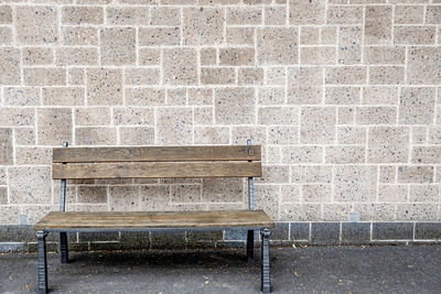 Empty bench against brick wall