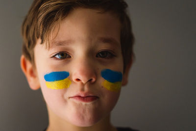 Portrait of a ukrainian boy with a face painted with the colors of the ukrainian flag.