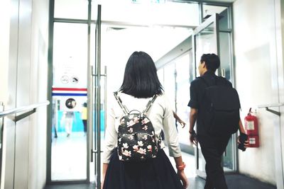 Rear view of woman standing by wall