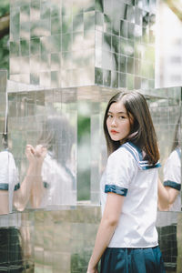 Portrait of woman standing by patterned glass