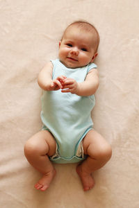 Portrait of cute baby girl lying on bed