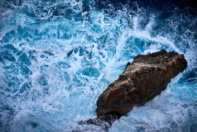 High angle view of waves on rock in sea