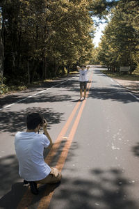 Rear view of man with umbrella on road