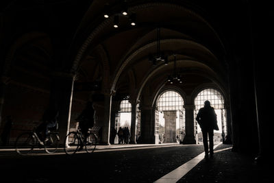 Silhouette man walking under bridge