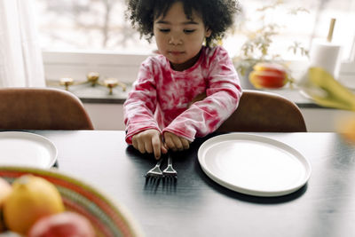 Girl looking at forks on table in kitchen