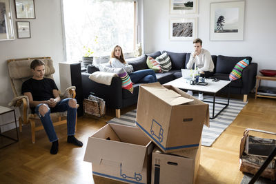 Siblings sitting in living room with cardboard boxes in new home