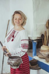 Portrait of smiling young woman standing at table