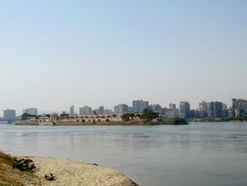 Sea and buildings against clear sky