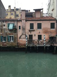 Buildings by river in city against sky