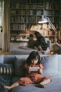 Down syndrome girl using smart phone on sofa at home