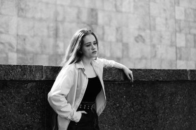 Young woman standing against wall