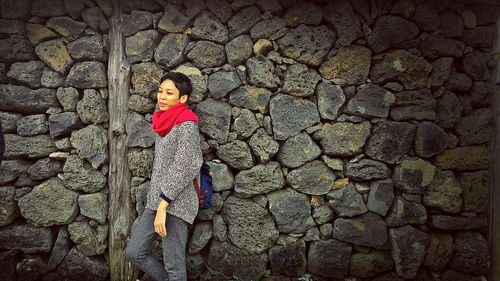 Portrait of woman standing by stone wall