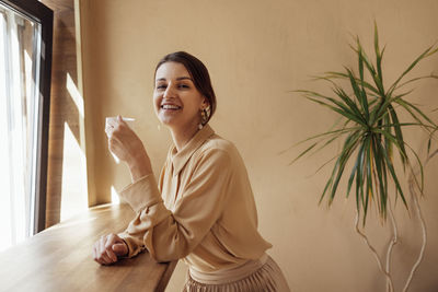 Portrait of young woman standing against wall