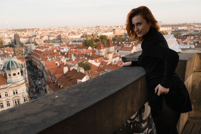 Young woman standing on townscape against buildings in city