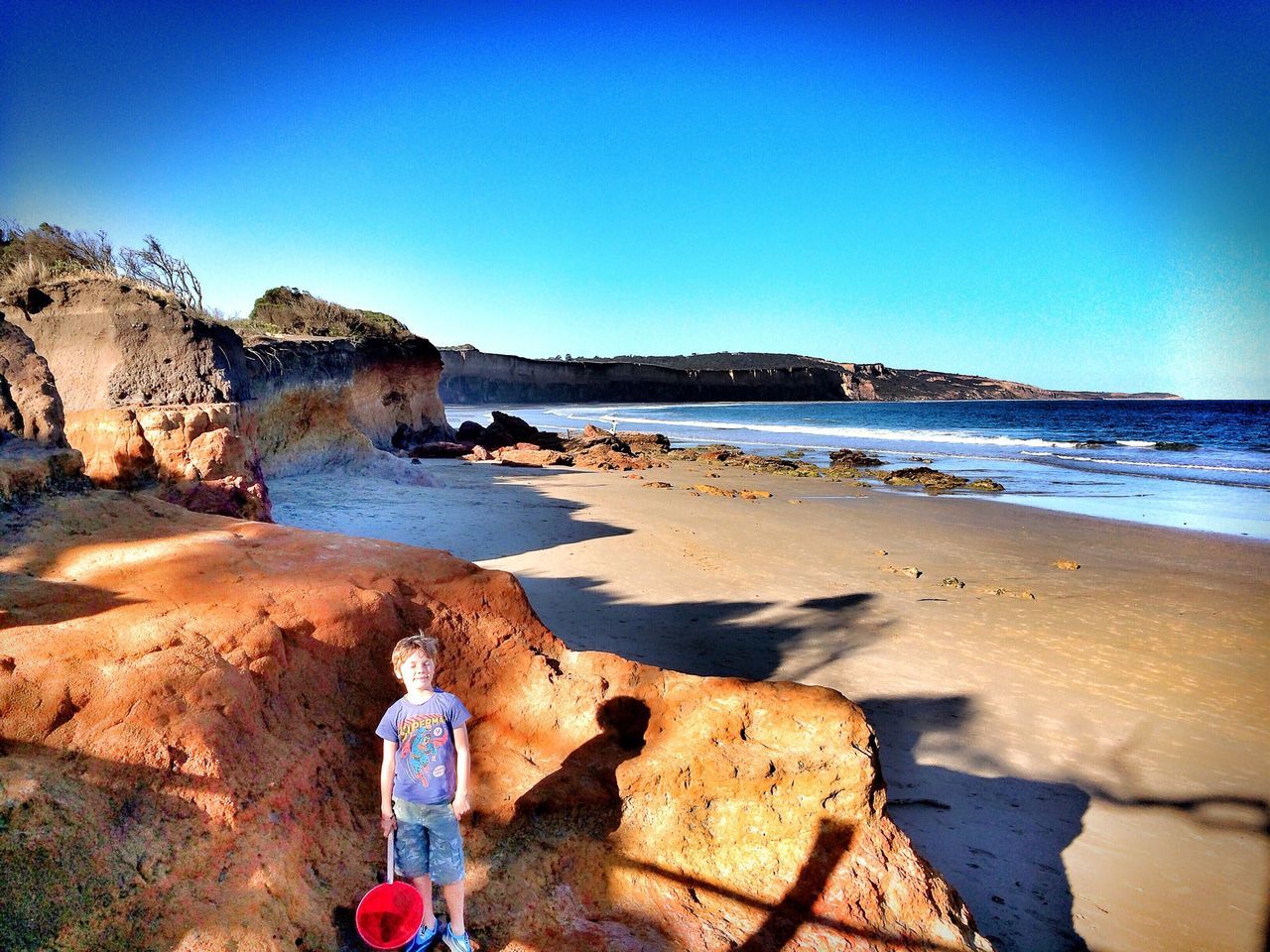 clear sky, sea, beach, water, shore, copy space, blue, sand, horizon over water, tranquility, scenics, tranquil scene, rock - object, beauty in nature, nature, sunlight, idyllic, outdoors