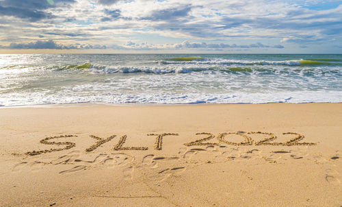 Text on beach by sea against sky