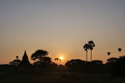 Silhouette trees on field against sky during sunset