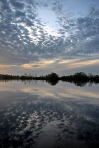 Reflection of clouds in calm lake at sunset