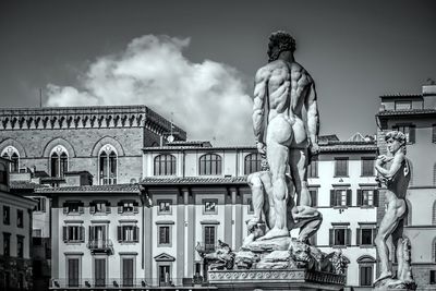 Statue against buildings in city against sky