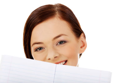 Close-up portrait of smiling woman with book against white background