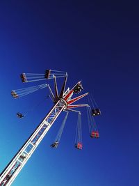 Low angle view of chain swing ride against blue sky