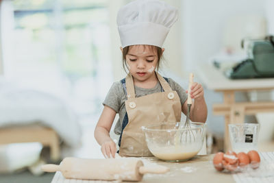 Girl holding ice cream on table at home