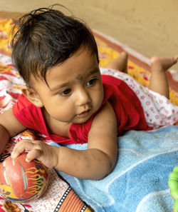 Cute baby playing with a ball looking away from camera. selective focus with background blur.