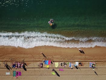 Directly above shot of friends relaxing on sand at beach