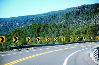 Road by trees against clear sky