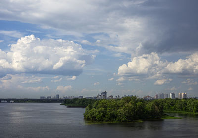 Scenic view of river by buildings against sky