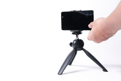 Close-up of hand holding camera over white background