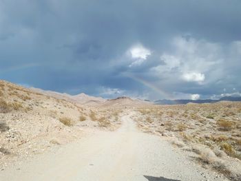 Dirt road amidst desert against sky