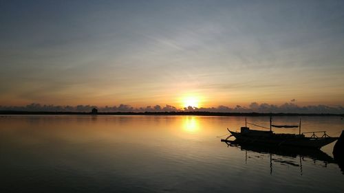 Boats in calm sea at sunset