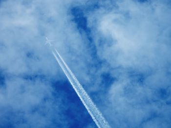 Plane with contrails in cloudy sky
