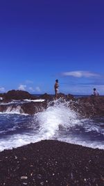 Man standing on beach against clear blue sky