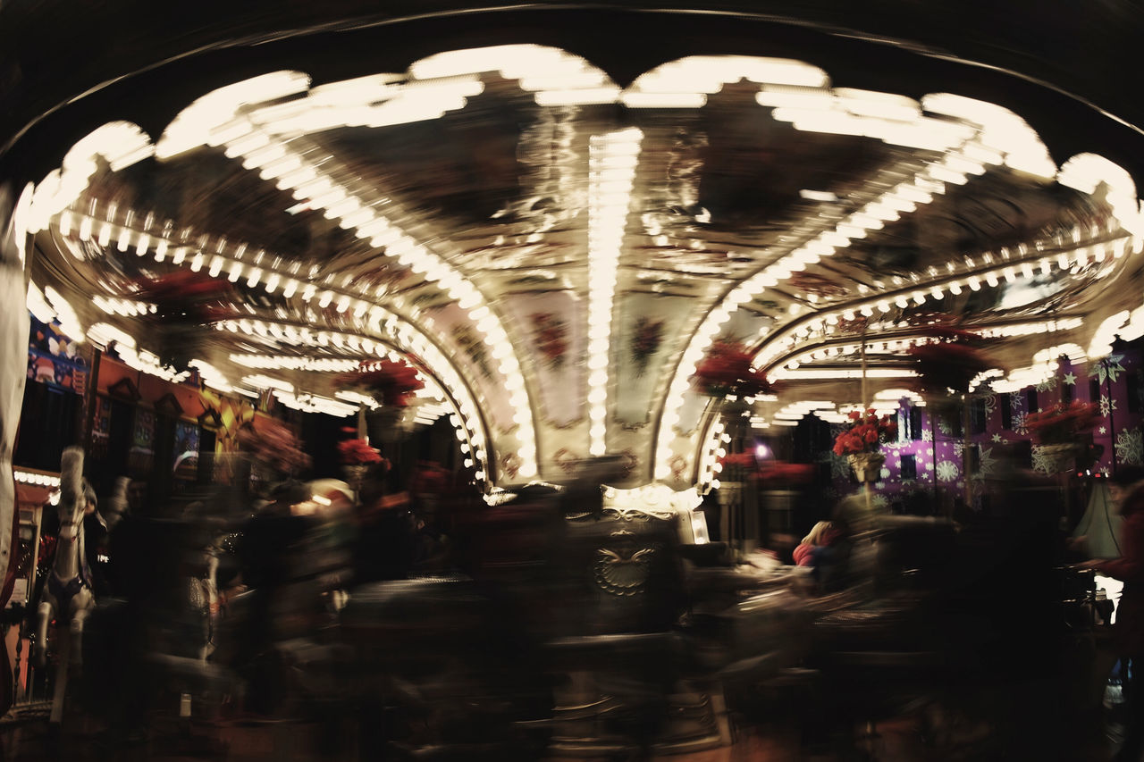 GROUP OF PEOPLE IN ILLUMINATED CAROUSEL AT NIGHT