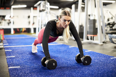 A woman doing push ups on the turf at the gym.