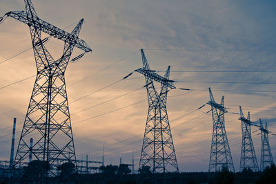 Low angle view of silhouette electricity pylon against sky during sunset