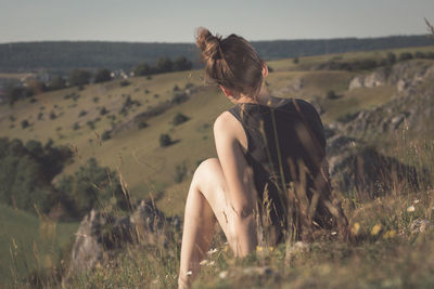 Rear view of woman sitting on grassy hill